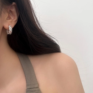 Dettaglio di orecchini a cerchio in argento con zirconi indossati da una modella