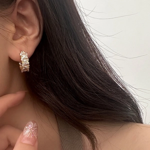 Dettaglio di orecchini a cerchio dorati con zirconi a marquise indossati da una modella