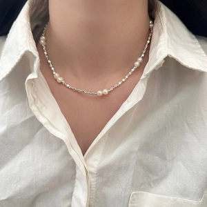 Elegant freshwater pearl necklace with silver beads on a woman wearing a linen shirt