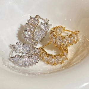 Dettaglio di orecchini a cerchio in oro e argento con zirconi incastonati su piatto ceramico