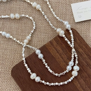 Minimalist freshwater pearl and silver cube bead necklace on an elegant wooden surface