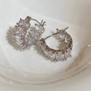 Dettaglio macro di orecchini a cerchio a C in argento con zirconi ovali incastonati