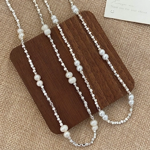 Minimalist natural pearl necklace with silver cube beads on vintage wooden background