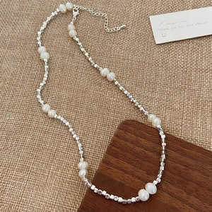 Detail of freshwater pearl necklace with silver beads on a rustic wooden stand