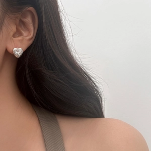 Détail d'une boucle d'oreille cœur en zircon portée montrant le design vintage argenté