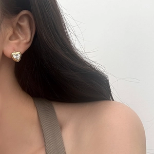 Gros plan d'une boucle d'oreille cœur en zircon doré portée, montrant un détail élégant