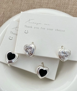 Détail de boucles d'oreilles cœur en zircon noir et blanc sur des cartes blanches