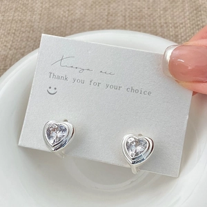 Détail macro de boucles d'oreilles créoles cœur en zircon rétro sur support blanc