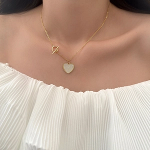 Elegante goldene Knebelhalskette mit Perlmutt-Herzanhänger an einem Modell