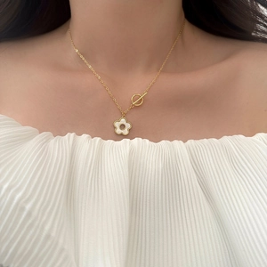 Elegante goldene Halskette mit weißem Blumenanhänger und T-Bar Verschluss auf einem Model