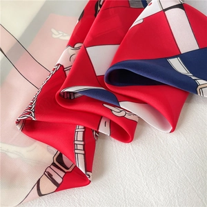 Detail of silk satin scarf showing chain patterns and smooth luxury texture in red and navy