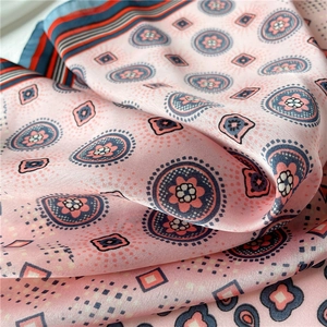 Gros plan d'un foulard en satin rose avec motifs paisley bleu marine et rayures