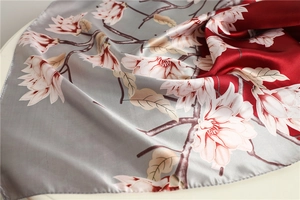 Detail of satin scarf with bicolor magnolia print and elegant silk-like glossy finish