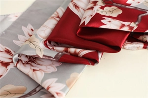 Close-up of dual-color floral satin scarf showing silky texture and magnolia flower patterns