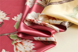 Close-up of silk scarf fabric showing white magnolia prints on red and yellow backgrounds