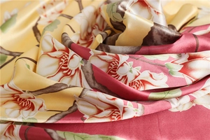 Close-up of silk scarf showing elegant magnolia floral print on satin fabric texture