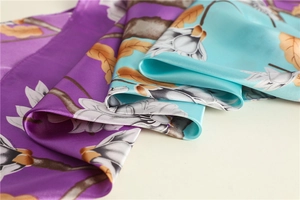 Close-up of dual-color floral print silk scarf with glossy satin finish and draped texture