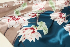 Detail view of floral magnolia pattern on premium satin silk scarf with peacock blue finish