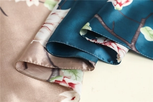 Close-up of satin silk scarf featuring vibrant floral prints and premium hemmed edges