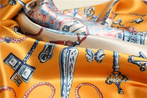 Macro detail of silk scarf showing vintage key patterns and satin fabric texture
