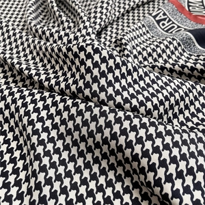 Dettaglio del foulard in seta pied-de-poule con bordo rosso e particolari del logo