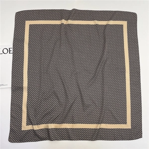 Black and white geometric pattern cotton silk scarf with beige borders flat lay view