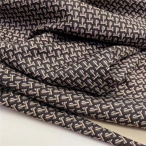 Detail of premium jacquard silk scarf with tri-color letter pattern and glossy texture
