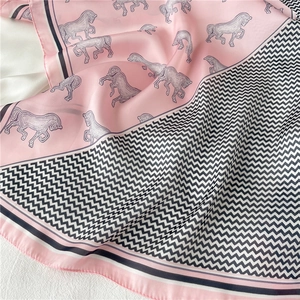 Dettaglio macro della sciarpa in seta con stampe di cavalli rosa e bordi chevron