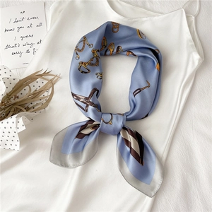 Blue silk scarf with golden equestrian horsebit print tied in an elegant bow