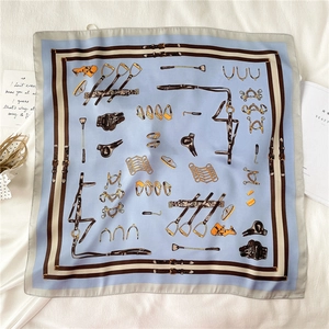 Detailed view of light blue square scarf featuring classic equestrian stirrup patterns