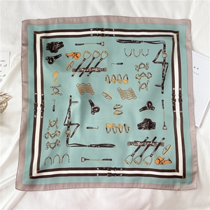 Detail of square silk scarf featuring equestrian motifs of horse bits and stirrups