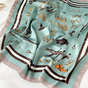 Detailed view of mint green silk scarf with equestrian patterns and striped edges