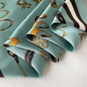 Detail of silk satin square scarf featuring turquoise equestrian print and horse bits