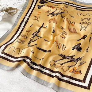 Detail of silk scarf with equestrian print and stripe border on a minimal background