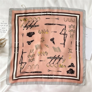 Detailed view of pink square silk scarf with classic equestrian patterns and gray borders