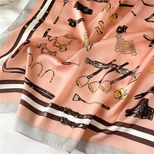 Detail of coral pink silk scarf with equestrian horse bit and stirrup pattern motifs