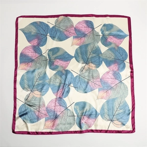 Detail of silk-like square scarf featuring layered heart-shaped leaf patterns and rich colors
