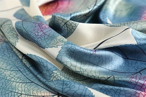 Detailed view of leaf pattern on silk-like scarf with blue and purple botanical prints