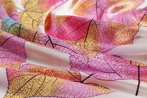 Detailed view of leaf pattern on soft satin silk scarf with elegant pink and orange tones