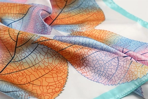 Macro shot of silk scarf with colorful leaf veins and light blue stitched edges
