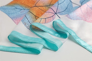 Close-up of leaf pattern silk scarf with vibrant gradient colors and satin rolled edges
