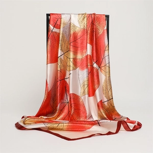 Detail of silk scarf with autumn leaf patterns and deep red borders for luxury accessory