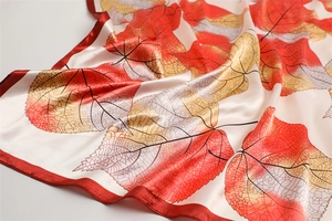 Close-up of luxury silk scarf showing maple leaf pattern and fine hemmed edges