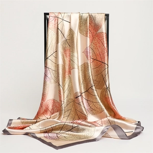 Detailed drape of champagne silk scarf with leaf patterns on elegant black frame