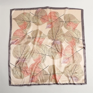 Detailed view of square silk scarf with realistic leaf patterns and elegant satin texture