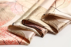 Macro shot of silk-like satin scarf featuring detailed reddish-brown leaf patterns
