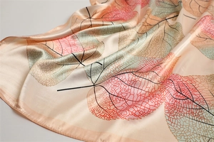 Detailed close-up showing silk texture and gradient leaf pattern on champagne scarf
