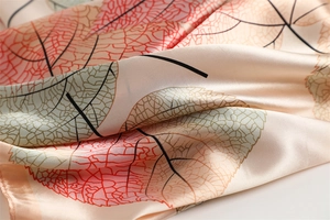 Detail of gradient leaf pattern and silky texture on a champagne square scarf