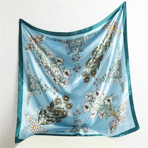 Detail of blue silk-like square scarf with floral print and deep teal border edges
