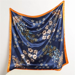 Detail of silk satin scarf with floral prints and orange edges in navy blue